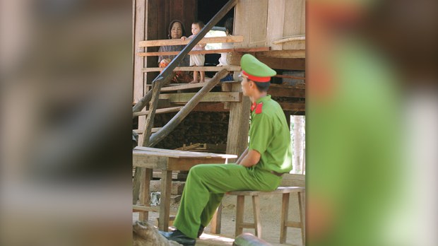 cong an canh cua Một cảnh sát ngồi canh bên ngoài ngôi nhà của người dân tộc thiểu số tại Buôn Đôn, tỉnh Daklak, Tây Nguyên của Việt Nam, ngày 15/3/2001. Ảnh: Reuters